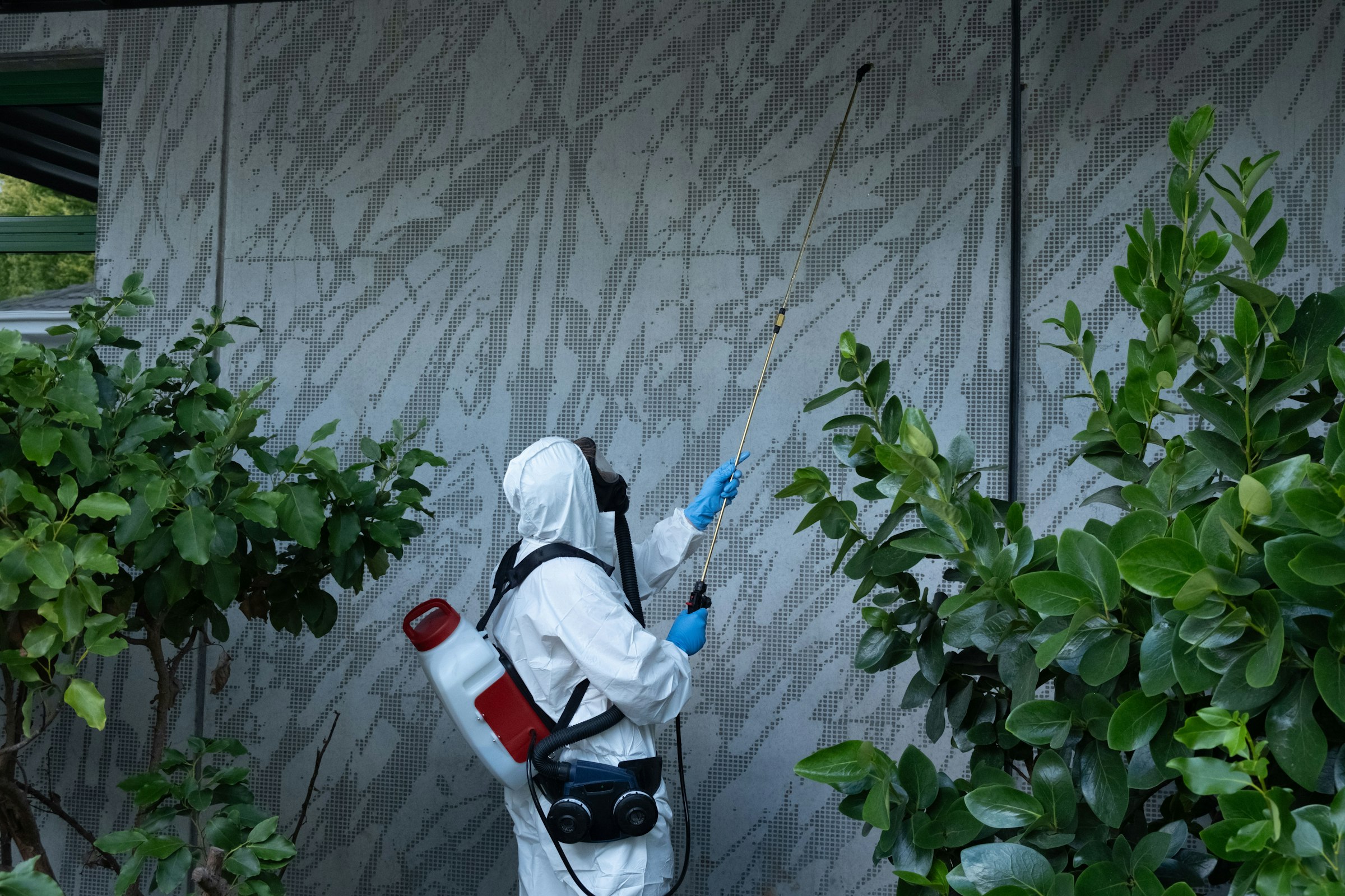 JK Facility Services team member spraying the outside of a building for pests.